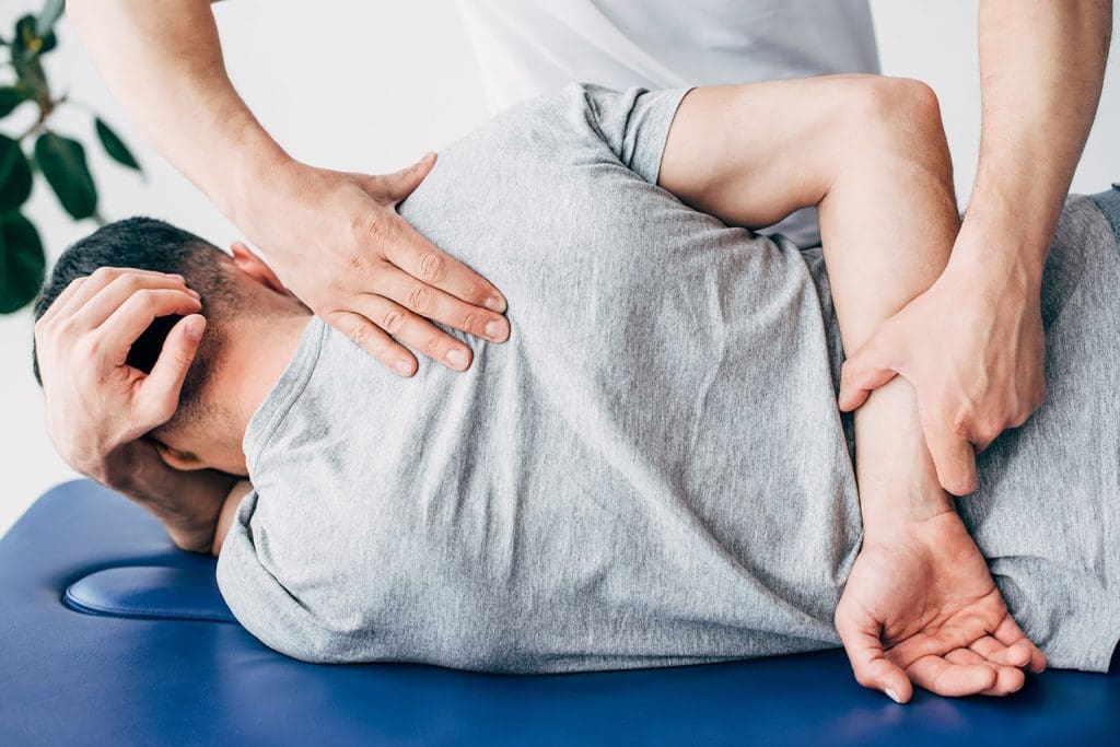 A chiropractor massaging the back of a man lying on a massage table